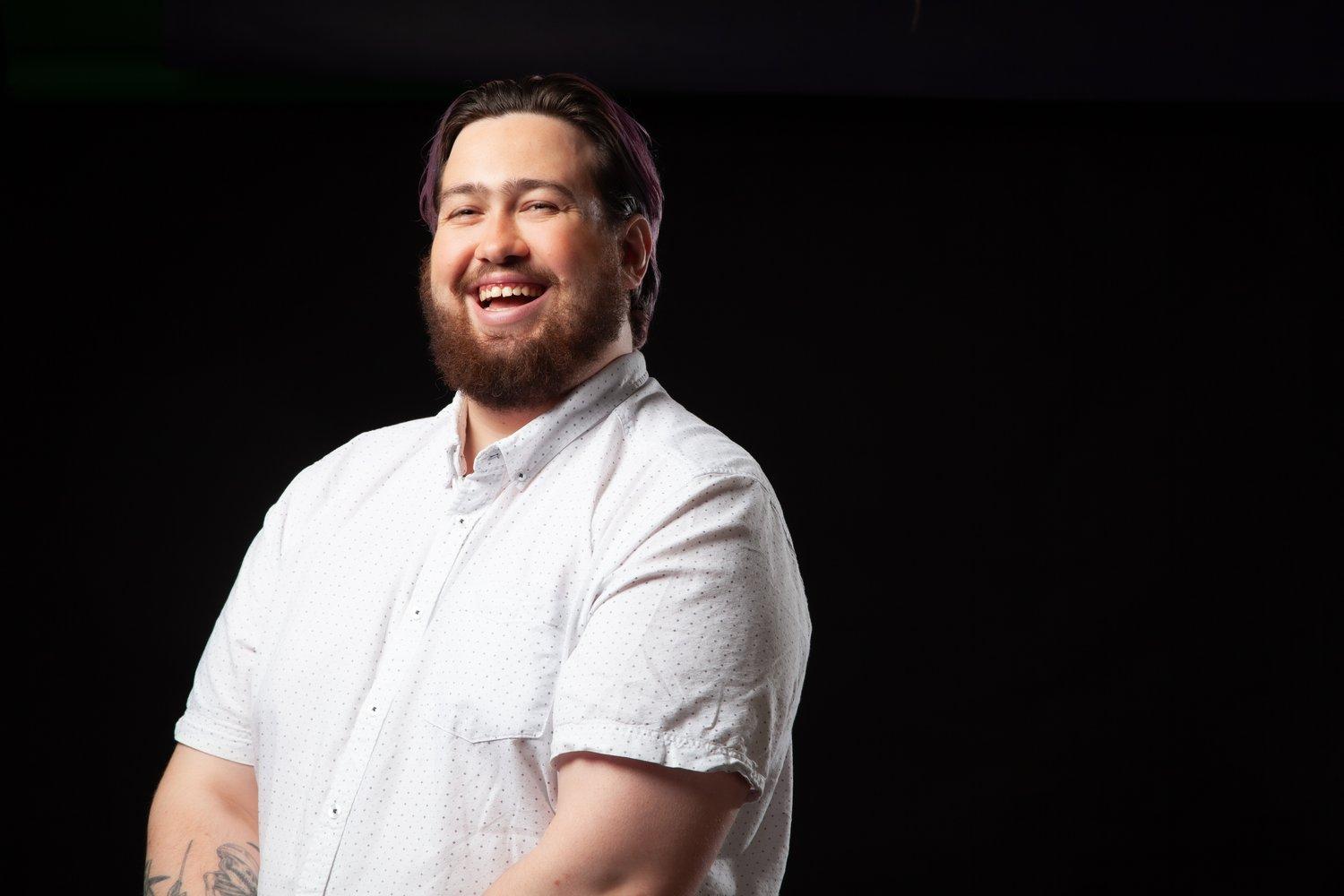 Matt laughing in a white shirt against a black background.