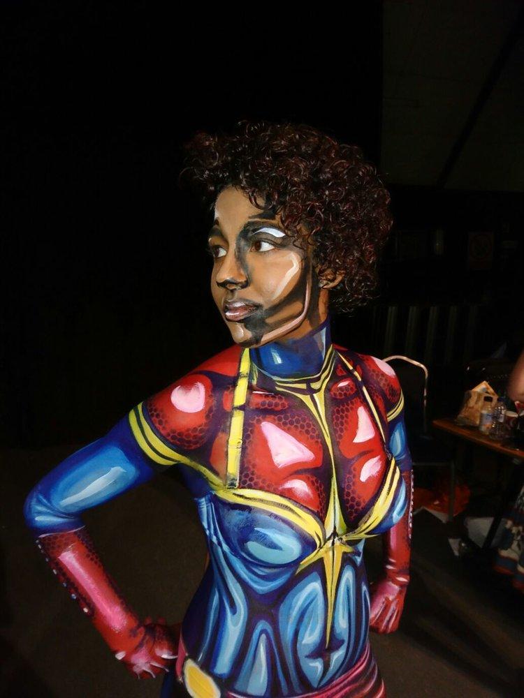 Rhyana posing with hands on hips, body painted as Ms. Marvel.