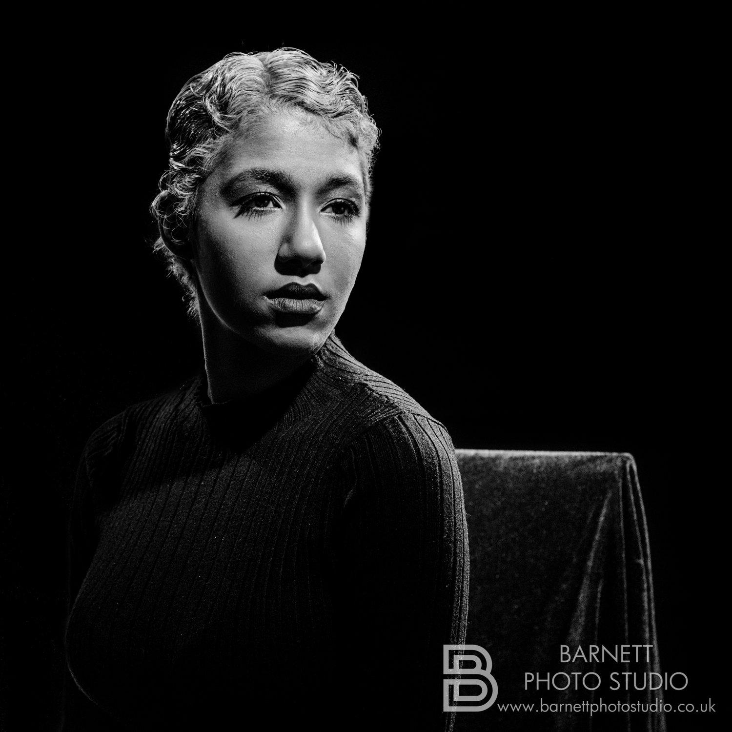 Rhyana in black and white with drawn-back, curled hair, looking pensively off camera.