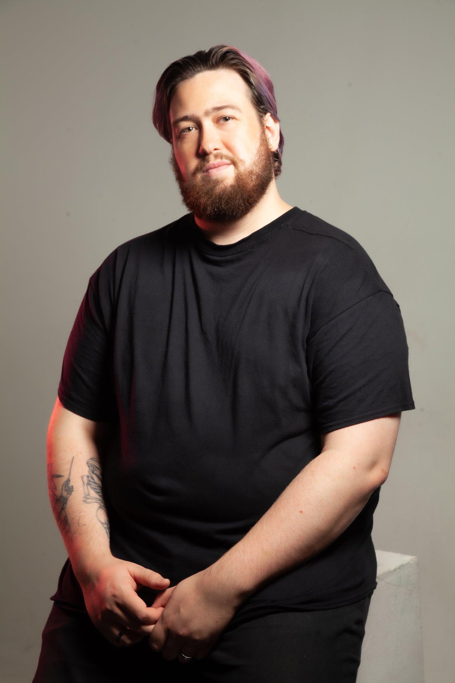 Matt sat in a black t-shirt against a white background, hands clasped.