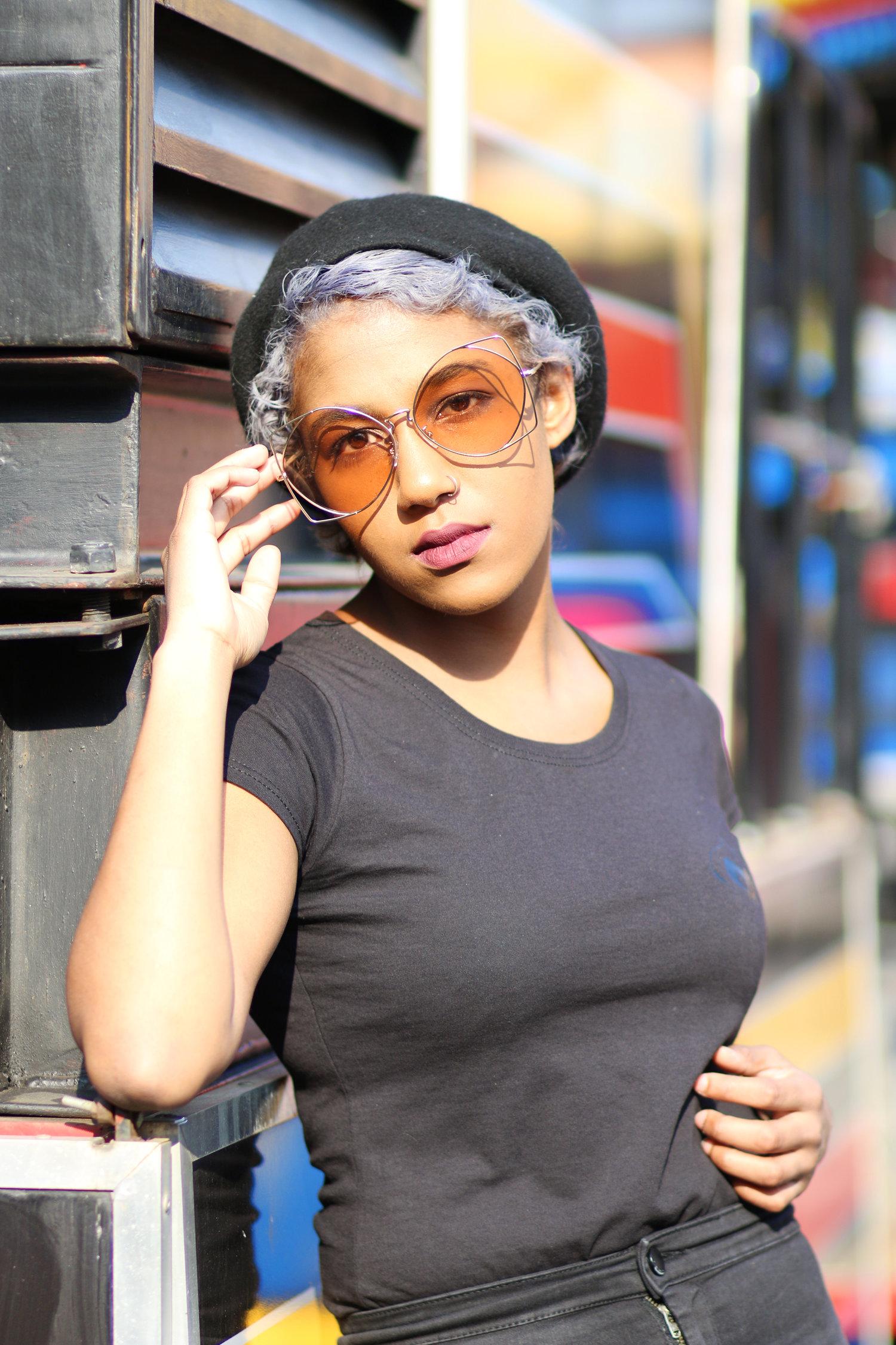 Rhyana leaning on one arm, looking towards the camera through amber sunglasses.