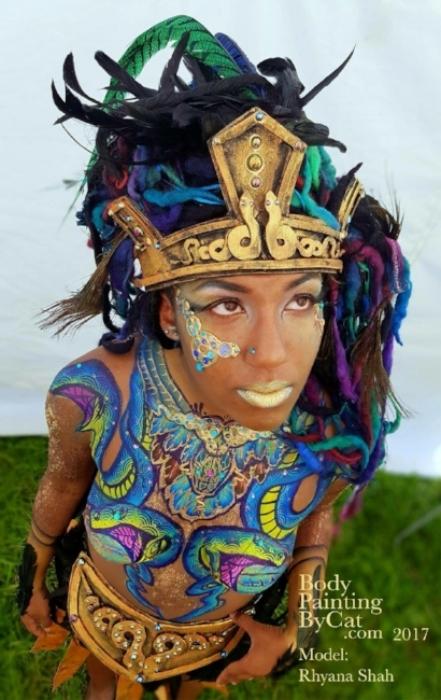 Rhyana from above with a blue and green chest body paint in a snake design.