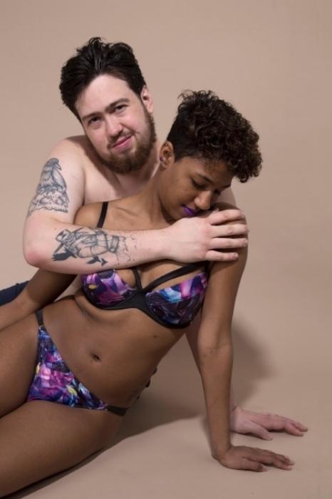 Rhyana in a purple floral bikini seated as Matt wraps a hand gently across their shoulders.