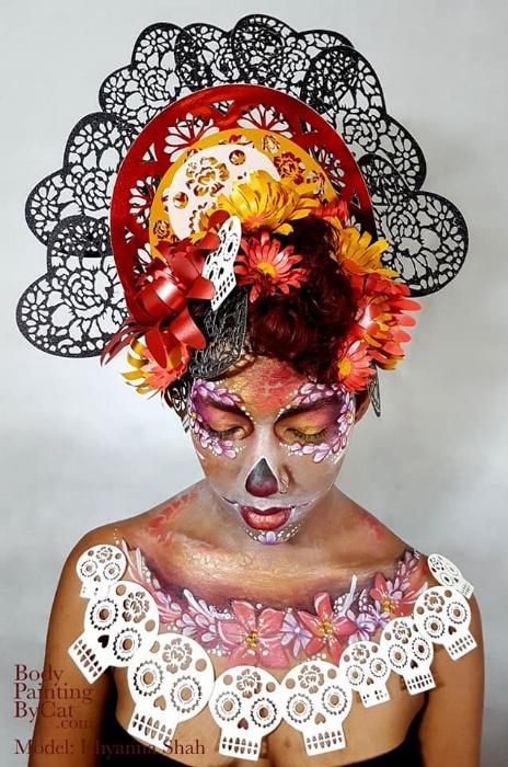 Rhyana dressed in black, white and red skull and flower motif looking down against a white background.