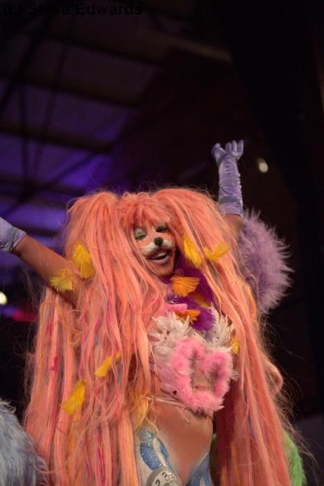 Rhyana with arms raised, dressed in a colourful fox outfit with long pink wig.