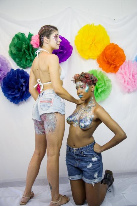 Rhyana kneeling in denim shorts by a fellow model, who has a hand laid on their shoulder.