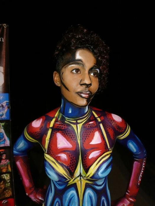 Rhyana posing with hands on hips, body painted as Ms. Marvel.