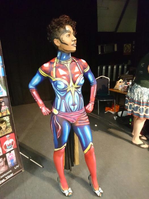 Rhyana posing with body painted as Ms. Marvel and green heels with white bows.