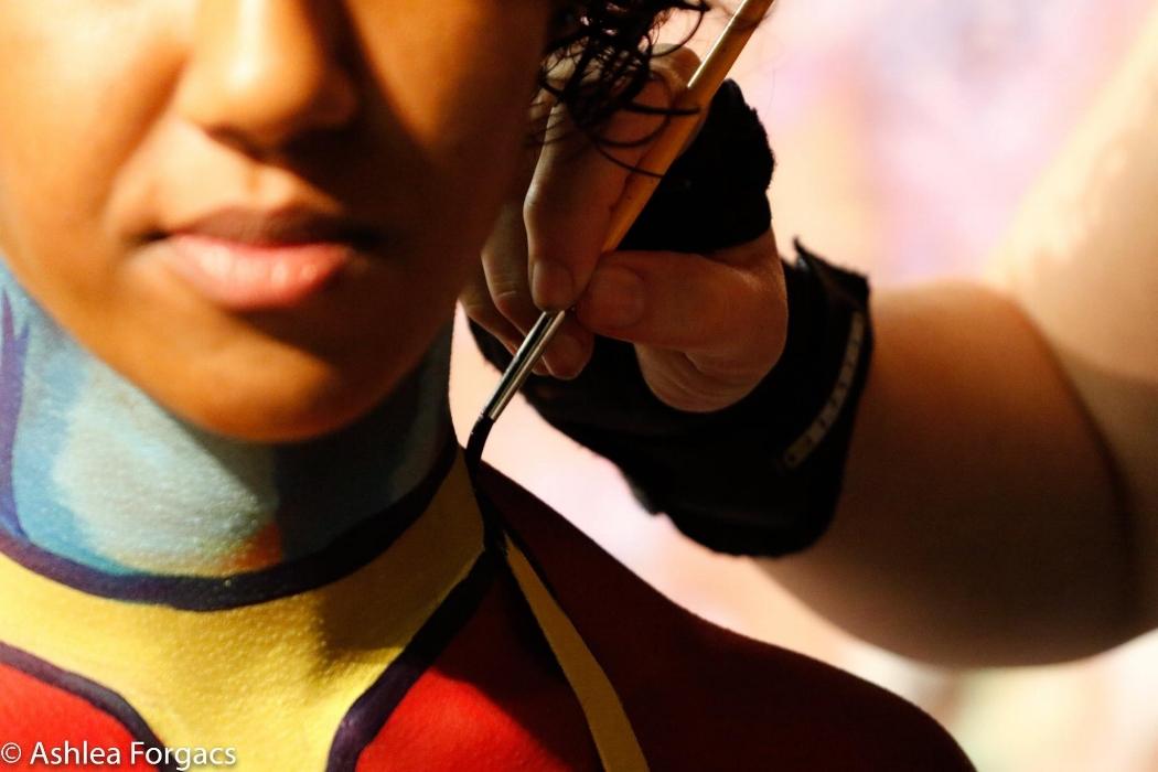 Clsoe up of Rhyana undergoing Ms. Marvel body painting on their neck.
