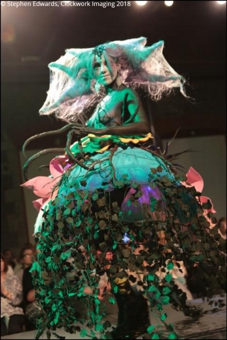 Rhyana in a forest-themed outfit with long claws, looking towards camera.