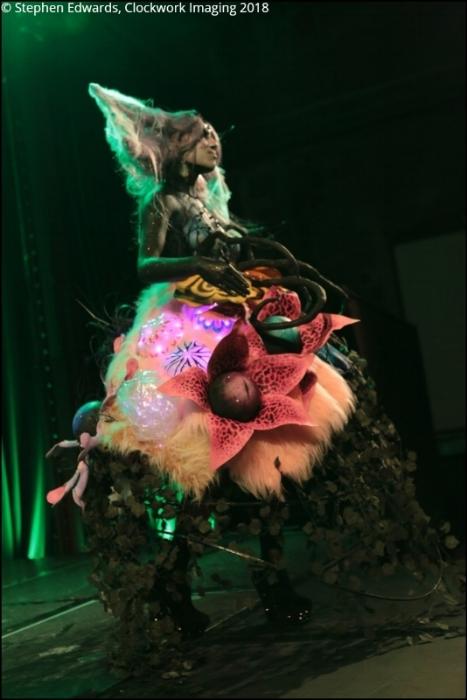 Rhyana in a forest-themed outfit with long claws under green lighting.