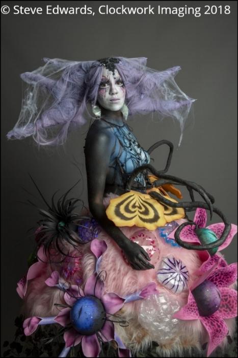 Rhyana in a forest-themed outfit against a grey background.