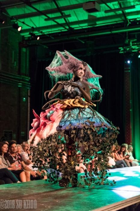 Rhyana in a spooky forest-themed outfit with long claws, walking with designer Tawny Lee.