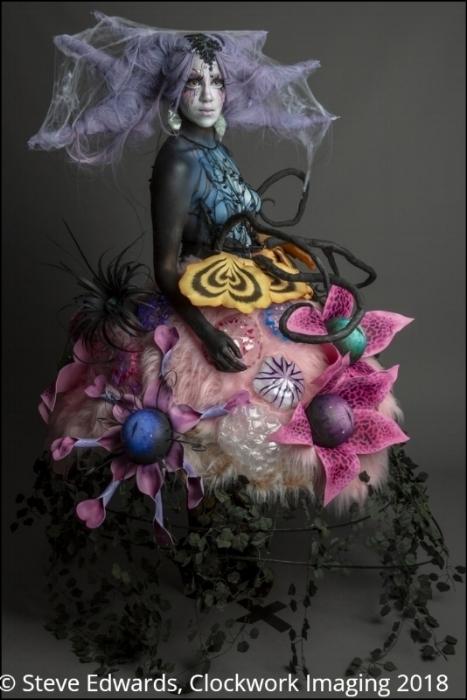 Mid shot of Rhyana in a forest-themed outfit against a grey background.