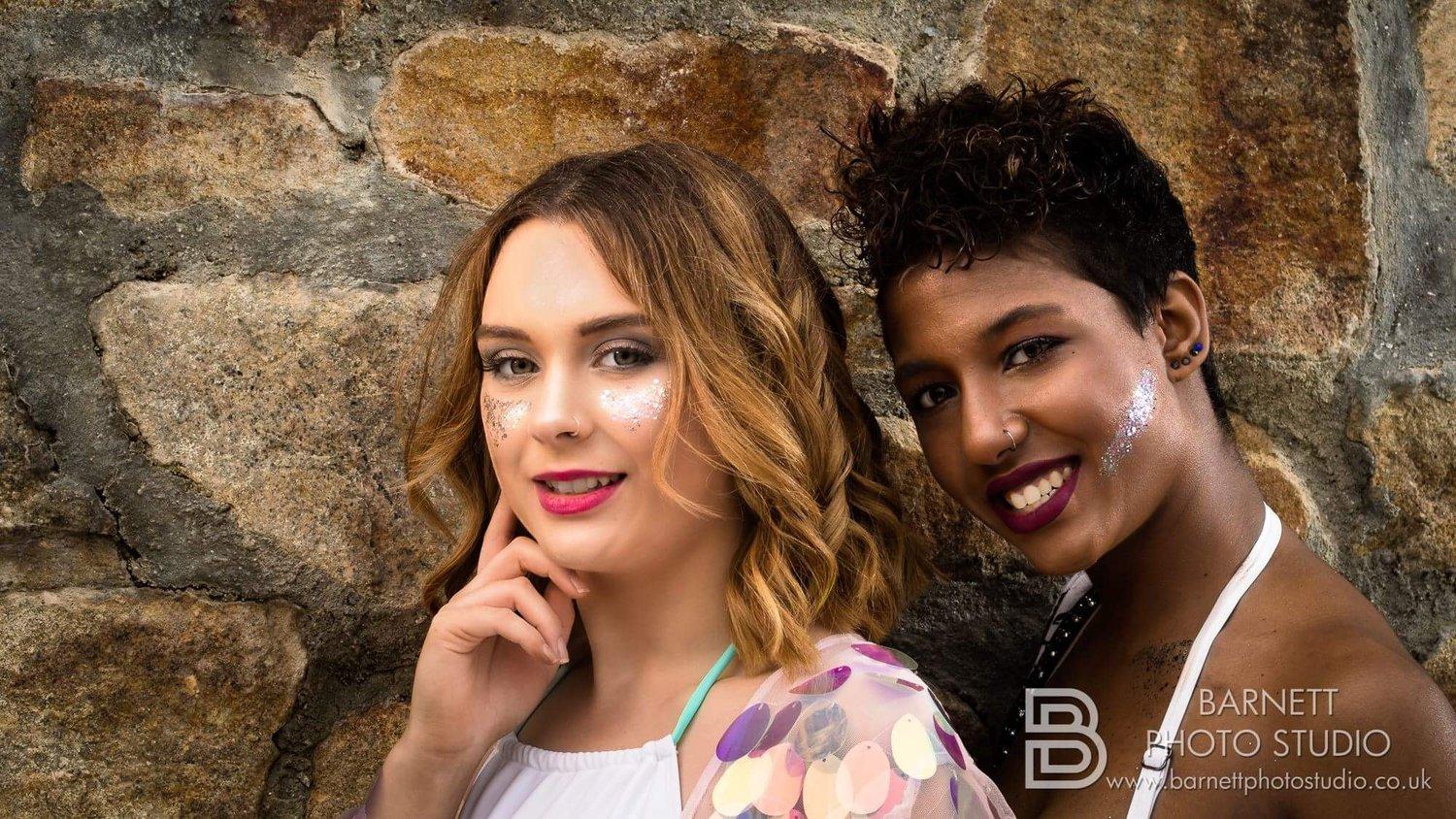 Rhyana and Megan leaning against a cobblestone wall.